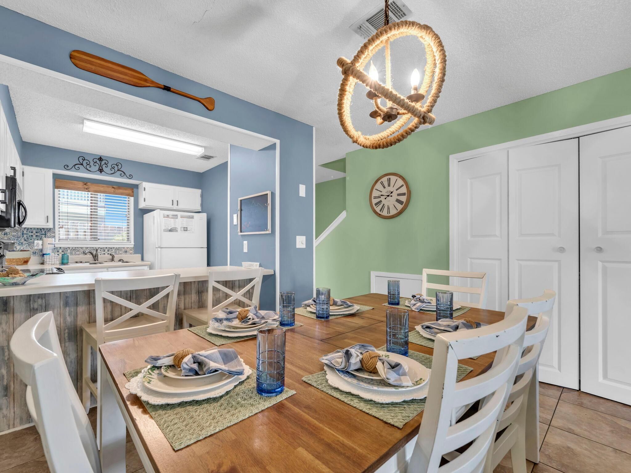 A dining area with a wooden table set for four, white chairs, and a chandelier.