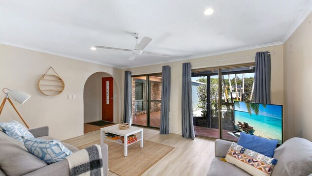 A modern living room with a large TV, two sofas, a coffee table, and a ceiling fan. - Family & Pet friendly Beachside with AC (Minyama)