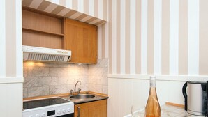 A compact kitchen with a stove, oven, sink, and striped wall.