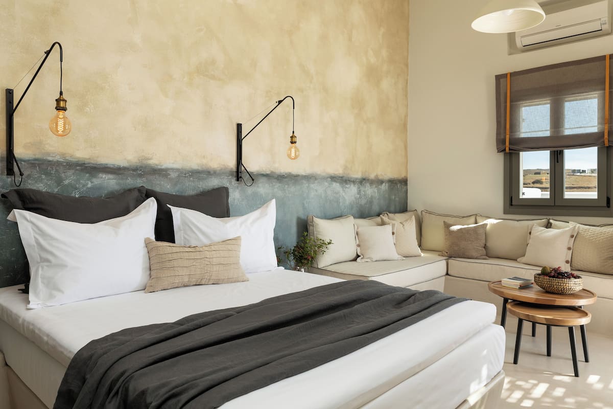 A bedroom with a bed, bedside tables, a sofa, and a window.