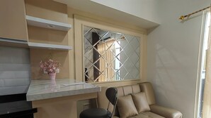 A modern kitchen with a marble countertop, a beige sofa, and a bar stool. - Podomoro Golf View By Arsakha Property (Gunung Putri)