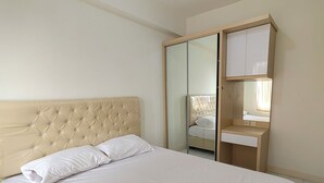 A bedroom with a bed, a wardrobe, and a vanity with a mirror. - Podomoro Golf View By Arsakha Property (Gunung Putri)