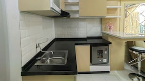 A compact kitchen with a built-in dishwasher, a stainless steel sink, and a small countertop. - Podomoro Golf View By Arsakha Property (Gunung Putri)