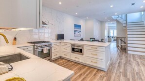 A modern kitchen with white cabinetry, a central island, and a built-in oven.