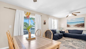 A dining area with a wooden table and chairs, a decorative bird sculpture, and a view of the outdoors through large windows. - Gulf Highlands 1160 (Panama City Beach)