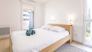 Un dormitorio con una cama, dos lámparas de noche, un ventanal y vistas a un edificio.