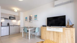 Una cocina moderna con microondas, estufa y comedor con sillas y mesa.