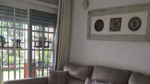 A living room with a beige sofa, a coffee table with a decorative item, and a window with curtains.