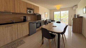 Una cocina moderna con armarios de madera, microondas, cafetera y comedor con mesa y sillas.