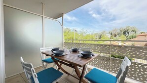 Un balcón con mesa y sillas, vistas a la vegetación y un cielo despejado.