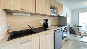 Una cocina moderna con armarios de madera, un lavamanos negro, un microondas y un lavavajillas.