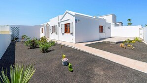 A white building with a flat roof, a small garden with cacti and plants, and a clear blue sky. - Villa Family by Villa Plus (Puerto del Carmen)