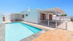 A modern house with a swimming pool, a covered patio with lounge chairs, and a small garden area. - Villa Family by Villa Plus (Puerto del Carmen)