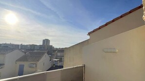 Una terraza en la azotea con una mesa y vistas de edificios circundantes.