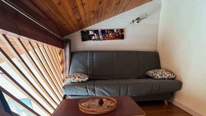 Una escalera de madera que lleva a una habitación con un sofá gris y una mesa redonda con un objeto decorativo.