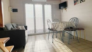 Una habitación con techo de madera, una mesa de comedor con sillas, un sofá y un televisor instalado en la pared.