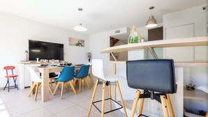 Une cuisine moderne avec un coin repas, un téléviseur à écran plat et une table à manger en bois, accompagnée de chaises.