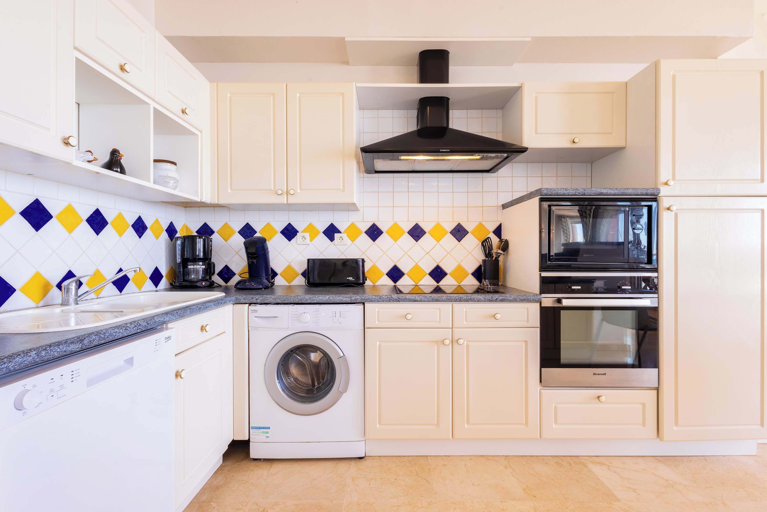 A compact kitchen with a washing machine, dishwasher, microwave, stove, and a coffee maker.