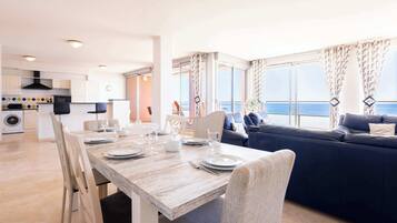 Een moderne woonkamer met een eethoek, een bank en uitzicht op zee.