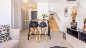 Een moderne keuken met een eetgedeelte, houten krukken, een centraal eiland en een trap naar een hoger niveau.