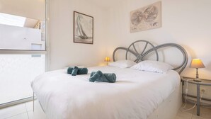 A bedroom with a bed, two bedside lamps, a map, and a sailboat painting on the wall. - Loggia Verde – Apartment with Terrace (Sérignan)