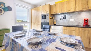 A modern kitchen with wooden cabinets, a built-in microwave, and a coffee machine. - Loggia Verde – Apartment with Terrace (Sérignan)