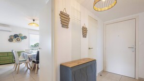 A dining area with a table and chairs, a wooden sideboard, and decorative wall art. - Loggia Verde – Apartment with Terrace (Sérignan)