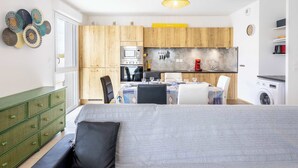 A compact kitchen with wooden cabinets, a microwave, and a washing machine. - Loggia Verde – Apartment with Terrace (Sérignan)
