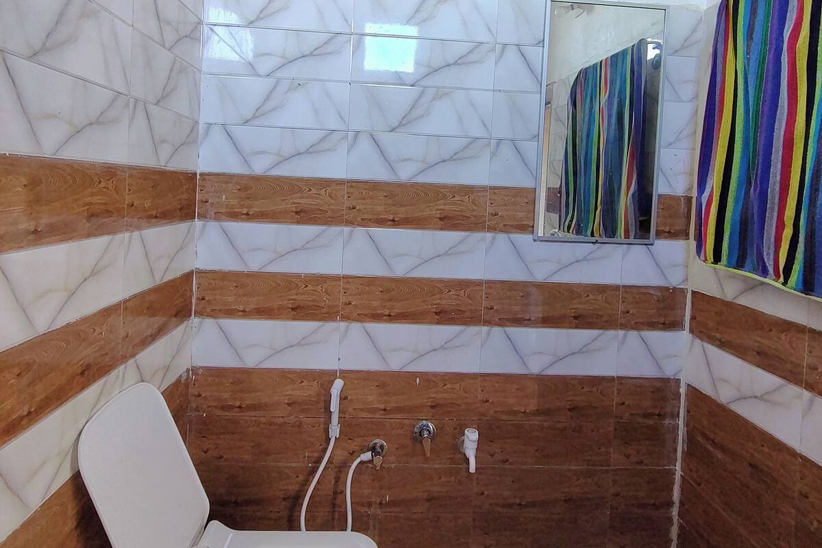 A bathroom with a toilet, wooden paneling, marble tiles, and a colorful striped towel.