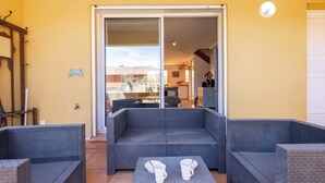 A patio area with a grey cushioned sofa, two white mugs, and a small table.