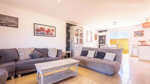 A living room with two sofas, a coffee table, a cabinet, and a dining area with a chair.
