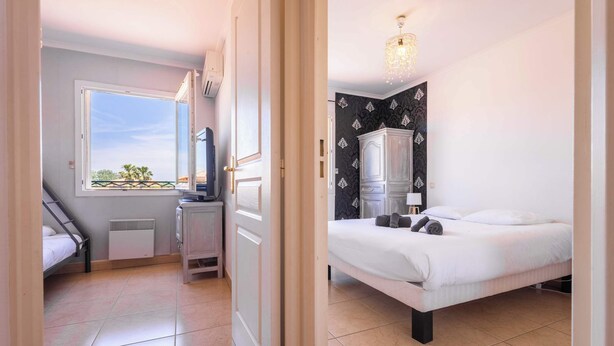A bedroom with a bed, a wardrobe, a desk, and a window with a view.