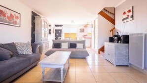 A modern living room with a sofa, a coffee table, and a kitchen area with a staircase.