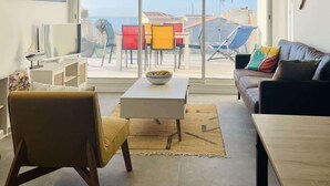 A modern living room with a large window, a sofa, a coffee table, and a television.