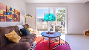 A living room with a brown leather sofa, a round coffee table, and a colorful abstract painting on the wall. - Villa Bianca – Spacious Apartment (Sérignan)