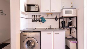A compact kitchen with a washing machine, two microwaves, a sink, and a coffee machine. - Le Clos Marin – Beautiful Flat in Secure Residence (Valras-Plage)