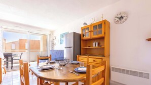A dining area with a wooden table, chairs, and a refrigerator. - Le Clos Marin – Beautiful Flat in Secure Residence (Valras-Plage)