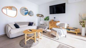 A modern living room with a sofa, coffee table, and armchair, a flat-screen TV, and a large mirror. - Valras 'Loc Archipel Panarea - Cap Horizon (Valras-Plage)