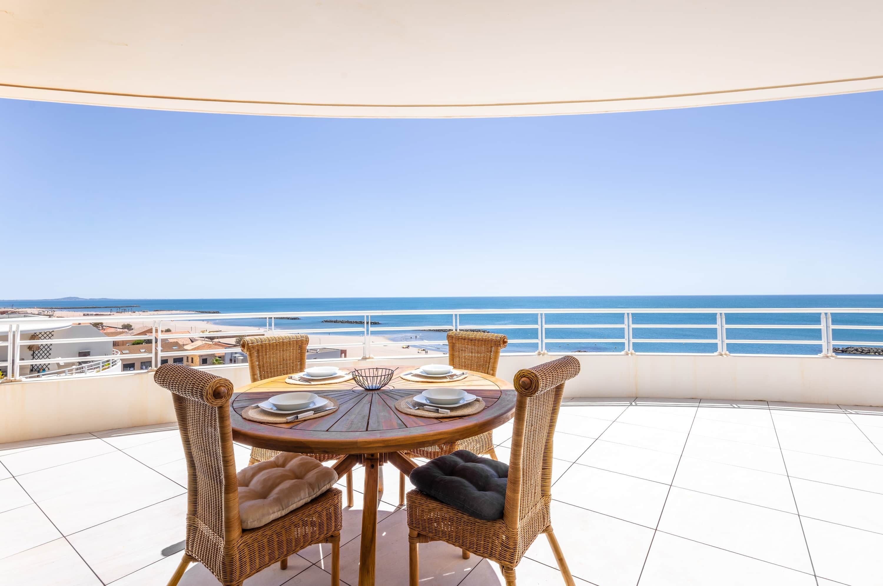 Une table ronde, des chaises et une vue sur la mer.