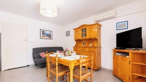 A dining area with a wooden table and chairs, a sofa, a TV stand, and a cabinet.