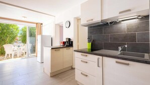 A modern kitchen with a built-in stove, a sink, and a dining area with chairs.
