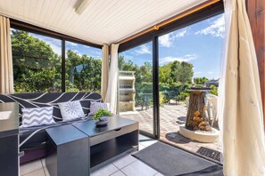 Une chambre moderne avec un canapé, une table basse et une vue sur le jardin grâce à de grandes fenêtres.