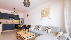 Un espacio habitable moderno con cocina, comedor y un sofá gris con cojines decorativos.