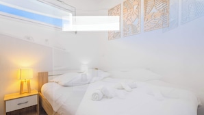 Una habitación de hotel con cama, mesita de noche, lámpara y decoración en la pared.