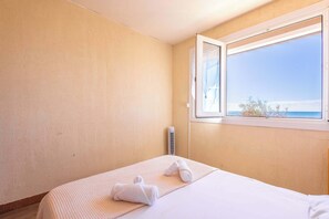 Quarto com cama, janela com vista e aquecedor fixado na parede.