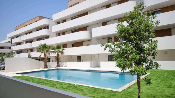 A modern multi-story hotel with a swimming pool, green lawn, and palm trees. - T2 with Terrace & Pool 300m from the Beach (Sérignan)