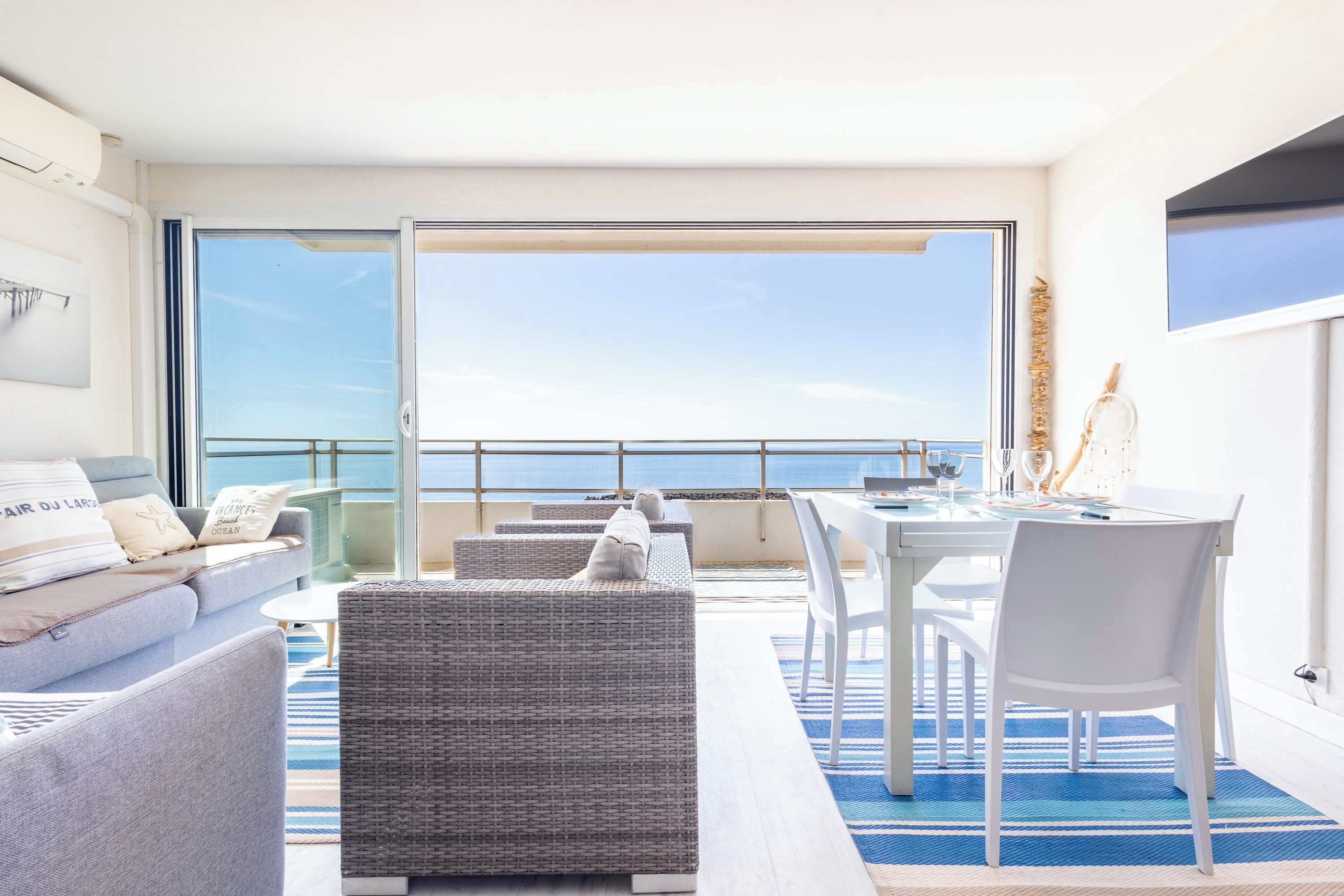 Ein Balkon mit einer Couch, Stühlen und einem Esstisch.