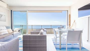 Ein Balkon mit einer Couch, Stühlen und einem Esstisch.