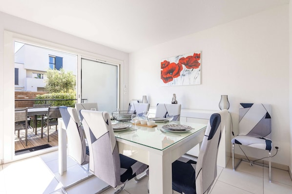 A dining area with a glass table, modern chairs, and a view of the outdoors.