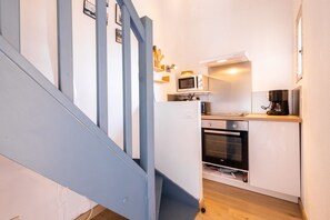 Een keuken met een magnetron, oven en koffiezetapparaat op een aanrecht.